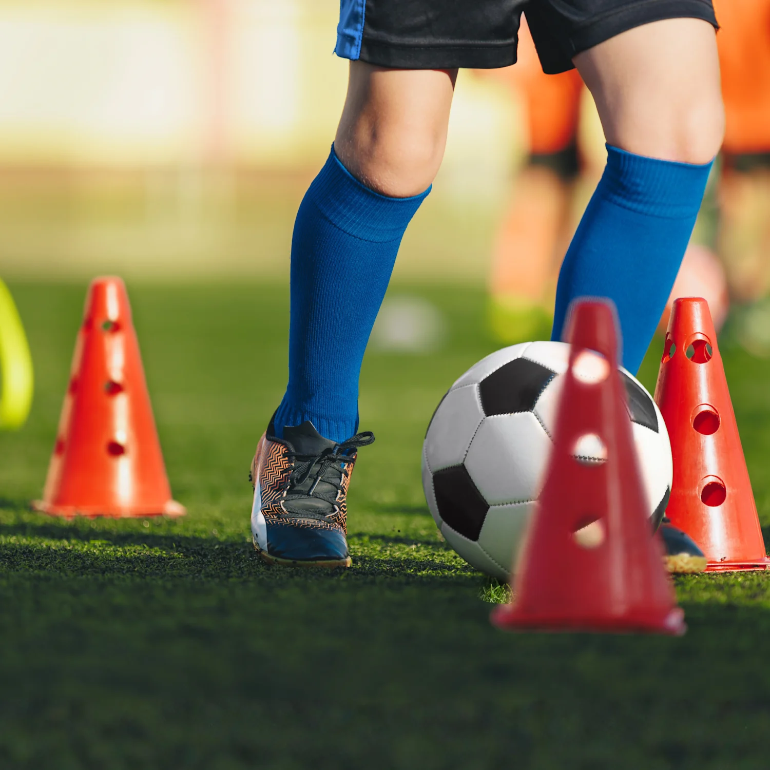 Child kicking a soccer ball through cones